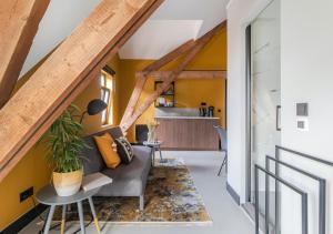uma sala de estar com paredes amarelas e um sofá cinzento em B&B De Oude Dorpsslagerij em Nuth