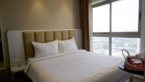 a bedroom with a large white bed with a window at RELOhomes Serviced Apartment in Mumbai