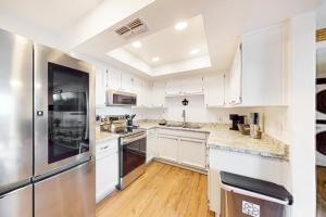 a kitchen with white cabinets and a stainless steel refrigerator at Sunbeam Condo in Scottsdale