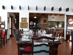 a dining room with a table and chairs and a woman at Geluksdam Guest House in Olifantshoek
