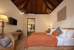 a bedroom with a bed and a chair and a television at Pradja Slumbung Villas in Nusa Penida
