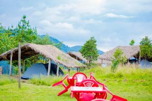 una sedia rossa seduta sull'erba accanto a una tenda di Kitabi EcoCenter a Gabegi