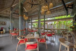 a restaurant with wooden tables and red chairs at Pradja Slumbung Villas in Nusa Penida