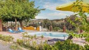- une piscine avec une table, des chaises et un parasol dans l'établissement Alojamiento Rural El Salto Villafranca de Córdoba by Ruralidays, à Cordoue