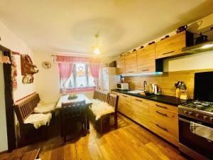 a kitchen with wooden cabinets and a table with two chairs at Chalúpka v Ždiari in Ždiar
