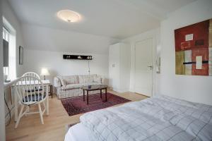 een witte slaapkamer met een bed en een bank bij Skovbakkens B&B in Aalborg