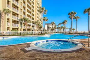 a swimming pool in front of a building with palm trees at Grand Panama Beach Resort #T1-1402 in Panama City Beach