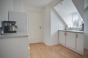 a white kitchen with a sink and a door at Skovbakkens B&B in Aalborg