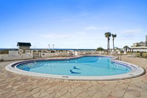 a large swimming pool with chairs and the ocean in the background at Emerald Towers by Panhandle Getaways in Destin