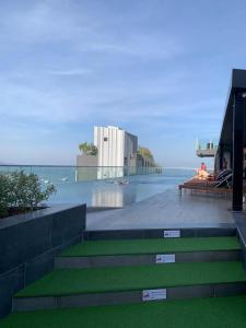 dos personas sentadas en un banco junto al océano en 泰国芭提雅thebase无边游泳池公寓, en Pattaya central