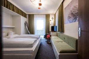um quarto de hotel com duas camas e um sofá em Garni Reider em Sesto