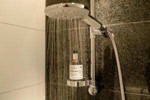 y baño con ducha y una botella de jabón. en Motel One Stuttgart-Feuerbach en Stuttgart