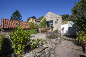una casa in pietra con un giardino di fronte di Moorside Cottage ad Ampleforth