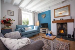 een woonkamer met een blauwe bank en een open haard bij Moorside Cottage in Ampleforth
