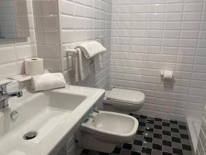 a white bathroom with a sink and a toilet at Green Hotel Motel in Vergiate