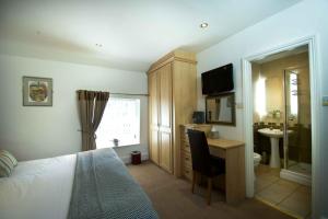 1 dormitorio con cama, escritorio y lavamanos en The Plough Inn, en Hathersage