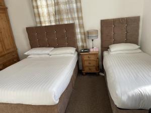 a bedroom with two beds and a night stand with a lamp at Diamonds Villa in York