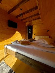 Cette chambre en bois comprend un grand lit blanc. dans l'établissement Hidden Cabin, à Brezoi