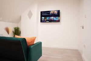 a living room with a green couch and a tv on the wall at Peaceful Luxury Apartment in Croydon
