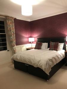 a bedroom with a large bed with a purple wall at Tullich House in Keith