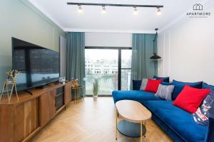 a living room with a blue couch and a flat screen tv at Rezydencja Wintera by Apartmore in Gdańsk
