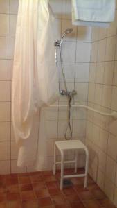 y baño alicatado con ducha y taburete. en Auberge Les Fontilles, en Coltines