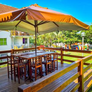 a table with chairs and an umbrella on a deck at Estada Inesquecível 17 Guarapari in Guarapari