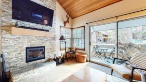 a living room with a fireplace and a stone wall at Sierra Megeve #7 Condo in Mammoth Lakes