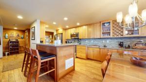 a kitchen with wooden cabinets and a bar with stools at Sierra Megeve #7 Condo in Mammoth Lakes