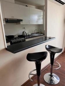 uma cozinha com dois bancos de bar e um fogão em Departamento 2D 1B Lircay em Talca