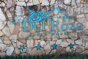 a sign for dezona guest house on a stone wall at Del Roza Guest House in Middelburg