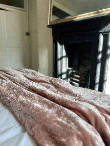 a blanket on top of a bed with a fireplace at The Cottage, Watergate, Sleaford in Lincolnshire