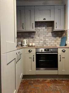 a kitchen with white cabinets and a black oven at The Cottage, Watergate, Sleaford in Lincolnshire