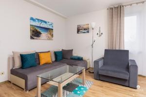 a living room with a couch and a chair at Jantar Apartamenty Sunny Olymp I in Kołobrzeg