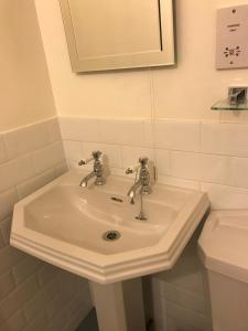 lavabo blanco en el baño con espejo en Tullich House, en Keith