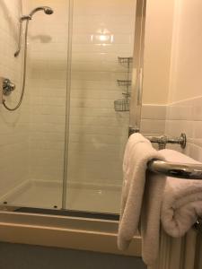 een badkamer met een douche, een bad en handdoeken bij Tullich House in Keith
