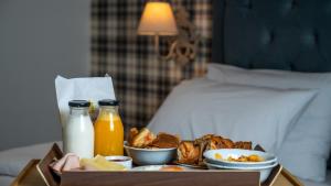 ein Tablett mit Essen mit Milch und Getränken auf dem Bett in der Unterkunft Brettania Hotel in Ioannina