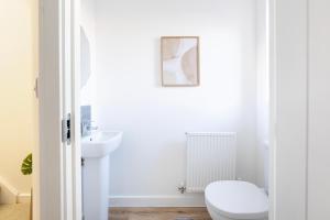 a white bathroom with a toilet and a sink at Fortified Three Bedroom Home Bristol 