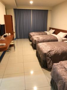 fila de camas en una habitación de hotel con escritorio en Lohas Seaview B&B, en Beigan