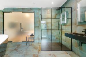 uma casa de banho com uma cabina de duche em vidro e um lavatório. em Westleigh em Ashtead