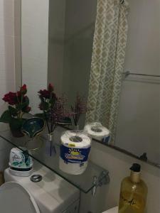 a bathroom with a toilet and a mirror and flowers at Unit 1537 Bahamas tower Azure Urban Resort Residence Paranaque City in Bacoor