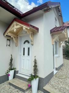 una pequeña casa con una puerta blanca y dos macetas en Rose Cottage en Prievidza