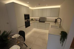 a kitchen with white cabinets and a table in it at Hideaway in Great Urswick
