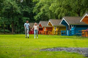a man and a woman walking in a yard with houses at Comfort Rooms by EuroParcs Het Amsterdamse Bos in Amstelveen