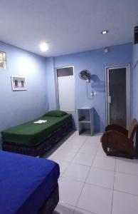 a blue room with a bed and a chair at Benara Shariah Homestay in Yogyakarta