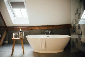 uma banheira branca na casa de banho com uma clarabóia em The Farmhouse at Redcoats em Stevenage