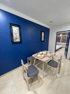 uma sala de jantar com uma parede azul e uma mesa e cadeiras em Coconut House em Malaca