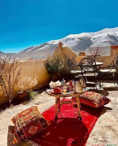 una mesa y sillas sobre una alfombra roja en el desierto en Chateau Imilchil en Imilchil