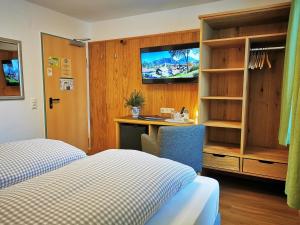 シュヴァンガウにあるホテル ヴァルトマンのベッド、デスク、テレビが備わるホテルルームです。