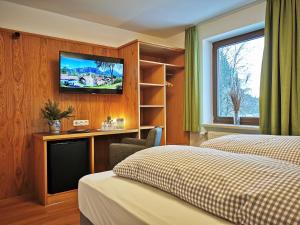 シュヴァンガウにあるホテル ヴァルトマンのベッド2台、壁掛けテレビが備わるホテルルームです。
